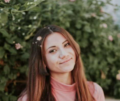 Smiling woman with long hair standing by greenery